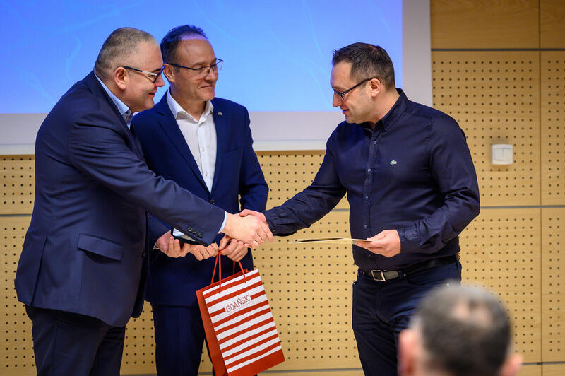 Piotr Kowalczuk - zastępca prezydent Gdańska oraz Leszek Paszkowski - dyrektor Gdańskiego Ośrodka Sportu wręczają nagrodę Łukaszowi Iwańskiemu - kierownikowi Kąpielisk Morskich