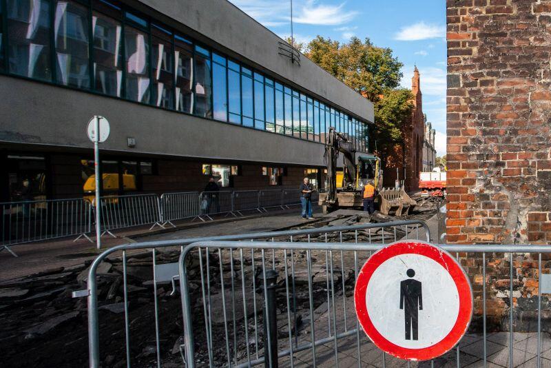 zamknięta ulica Elżbietańska, na barierkach znak zakazu ruchu pieszych, na dalszym planie widać koparkę kruszącą asfaltową nawierzchnię