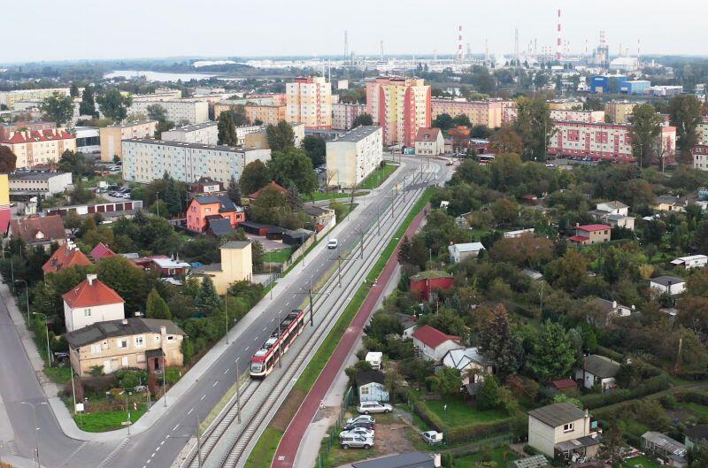 Ulica Stryjewskiego z lotu ptaka po modernizacji, widać tramwaj, jasne chodniki samochody. Bloki Stogów oświetlane śeiatłem zachodzącego słońca, obok torowiska ogródki działkowe