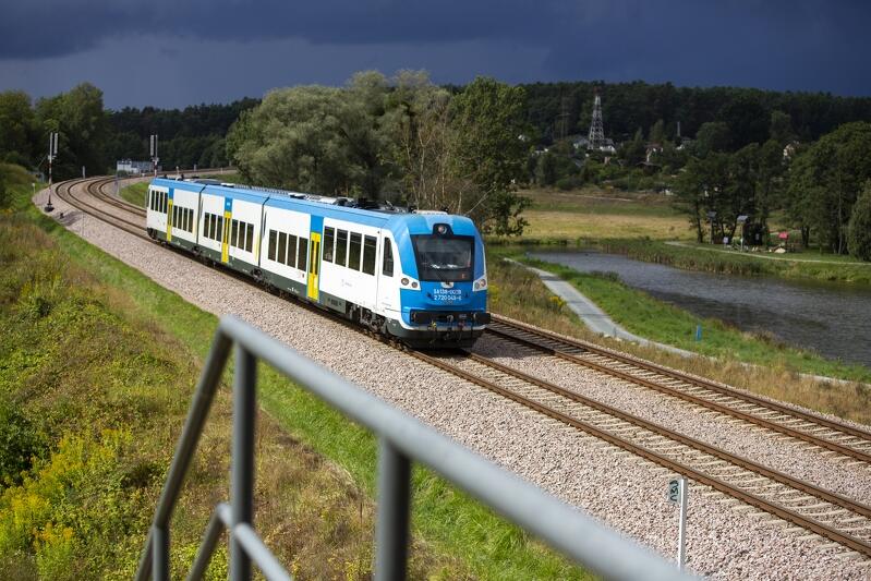 po torach jedzie skład kolejowy, w tle zbiornik wodny kiełpinek
