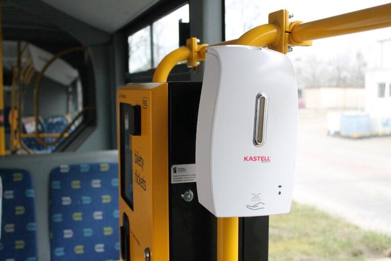 Biały dozownik umieszczony w autobusie obok kasownika