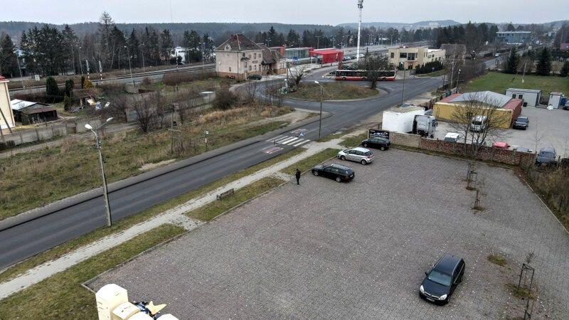 Węzeł Osowa widziany z góry. Na pierwszym planie praktycznie pusty parking, dalej rondo i budynki