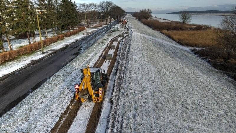 koparka na budowanym pasie drogi rowerowej na wale, za wałem Wisła