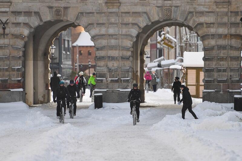 kilku rowerzystów jedzie zaśnieżonym Długim Targiem