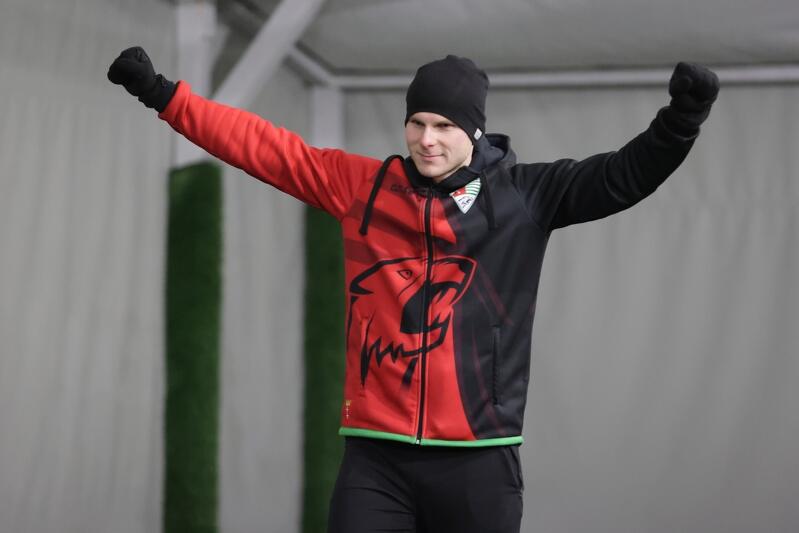 Młody mężczyzna w czapce i dresie ma wyciągnięte ręce ku górze