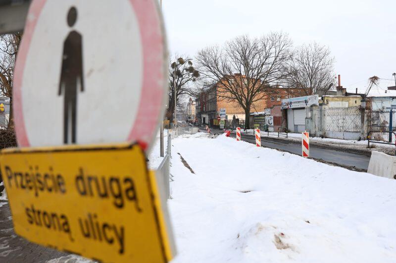 Znak zakazu ruchu pieszych, barierka, w tle ulica i miejsce prac wodociągowych przysypane śniegiem
