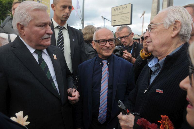 trzech mężczyzn w marynarkach rozmawia ze sobą serdecznie na placu Solidarności w Gdańsku