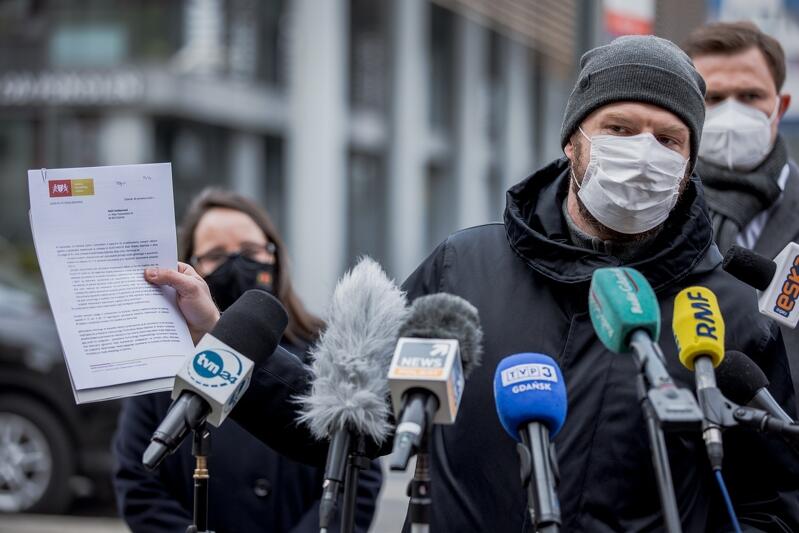 mężczyzna w maseczce, w jednej ręce plik papierów