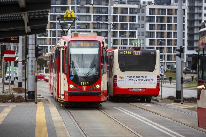 na zdjęciu widać przód tramwaju biało-czerwonego, mijanego przez biało - czerwony autobus komunikacji miejskiej