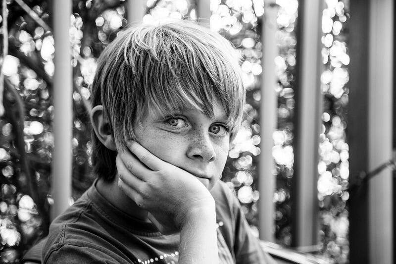 Chłopiec opierający głowę o rękę, zdjęcie czarno białe