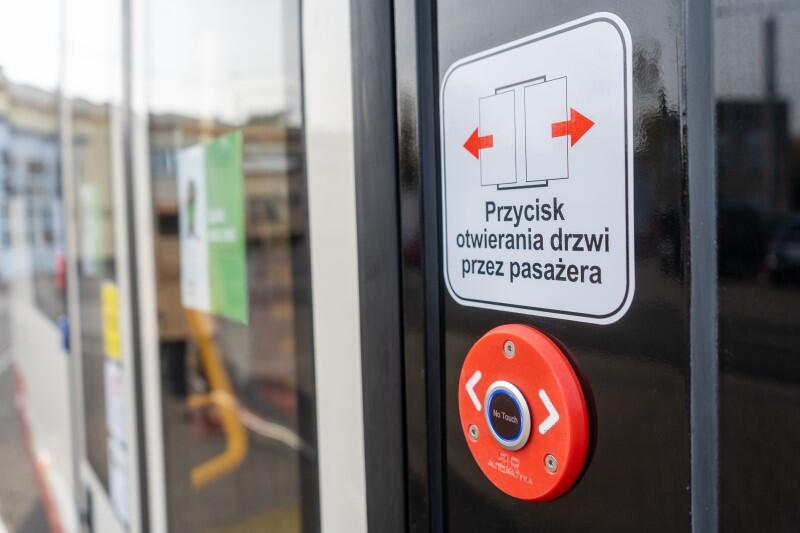 Fragment drzwi tramwaju z napisem przycisk otwierania drzwi przez pasażera 