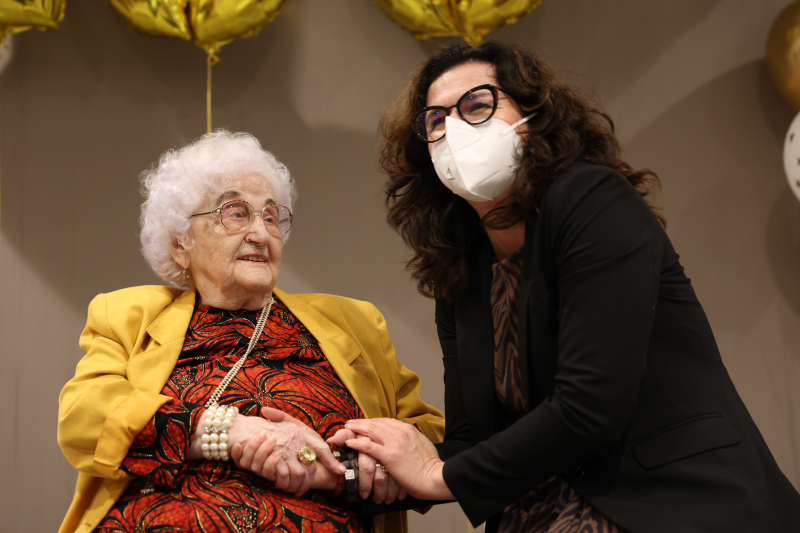 Sędziwa kobieta, elegancko ubrana obok kobieta w średnim wieku z długimi ciemnymi włosami