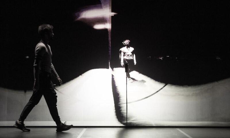 biało-czarne zdjęcie impresja: tancerz w świetle, idzie wzdłuż ściany