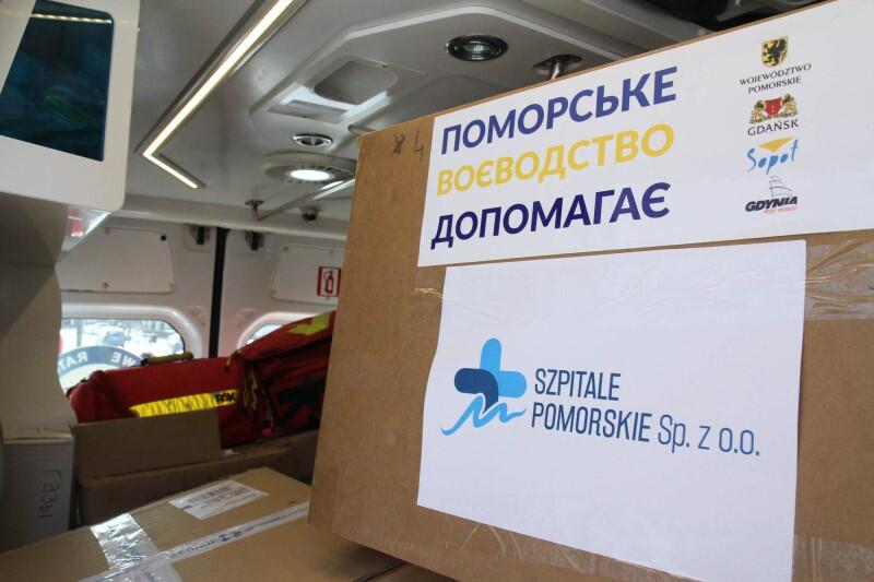 Wnętrze busa, w środku kartony z napisem Szpitale pomorskie