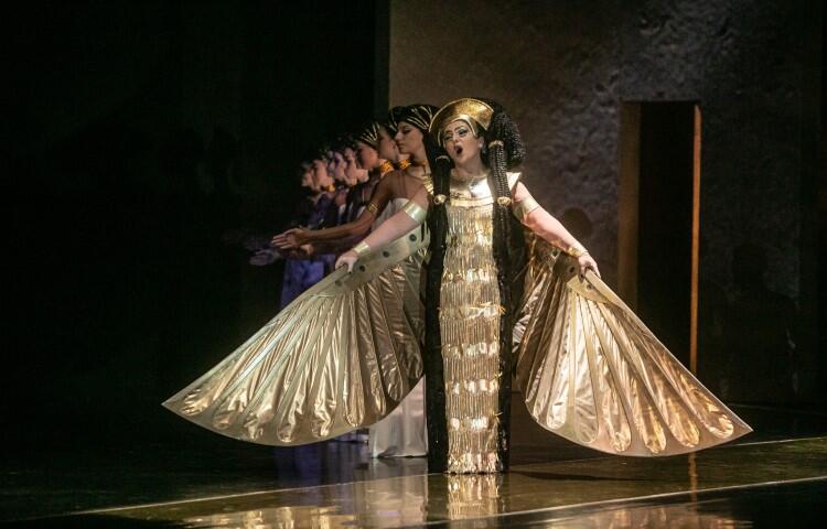 kobieta na scenie w złotym kostiumie z rękawami w kształcie skrzydeł