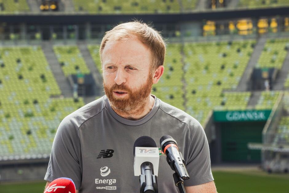 Rudy mężczyzna z brodą, na tle trybun stadionu Polsat Plus Arena Gdańsk 