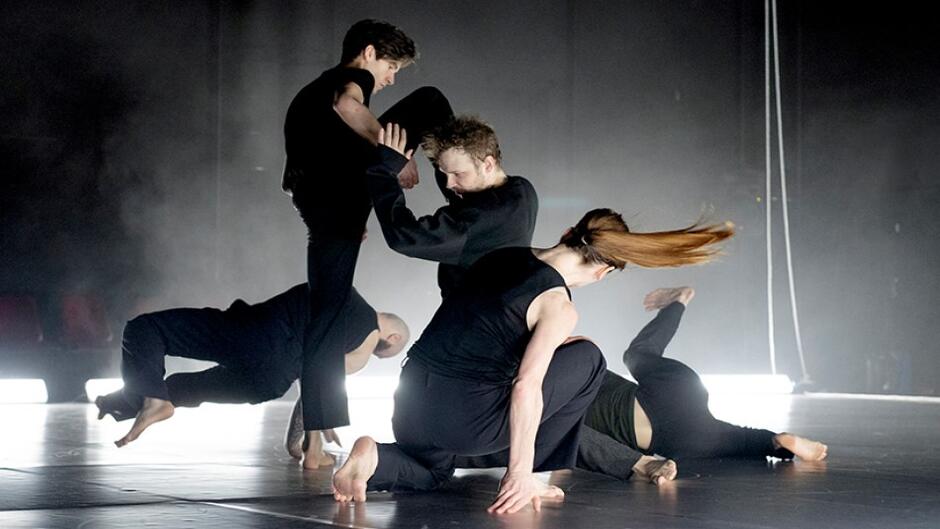 scena, pięciu tańcerzy ubranych w czarne stroje podczas występu