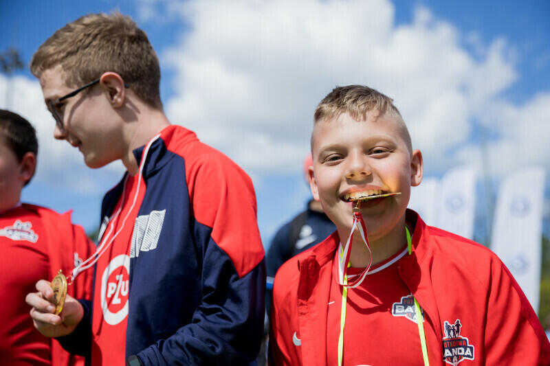 chłopiec trzyma medal w zębach, uśmiechając się przy tym