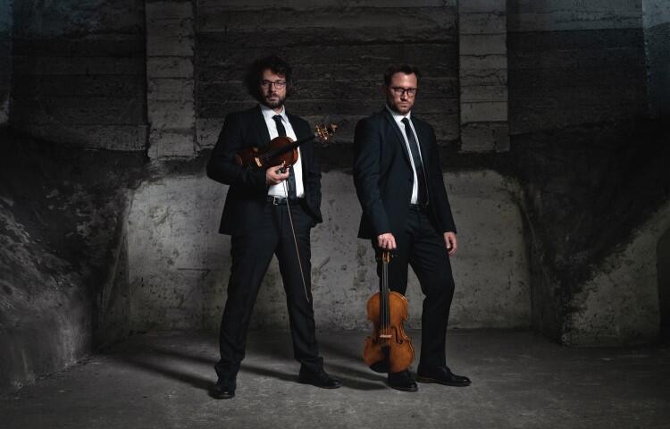 Two men in suits, one holding a violin and the other a viola