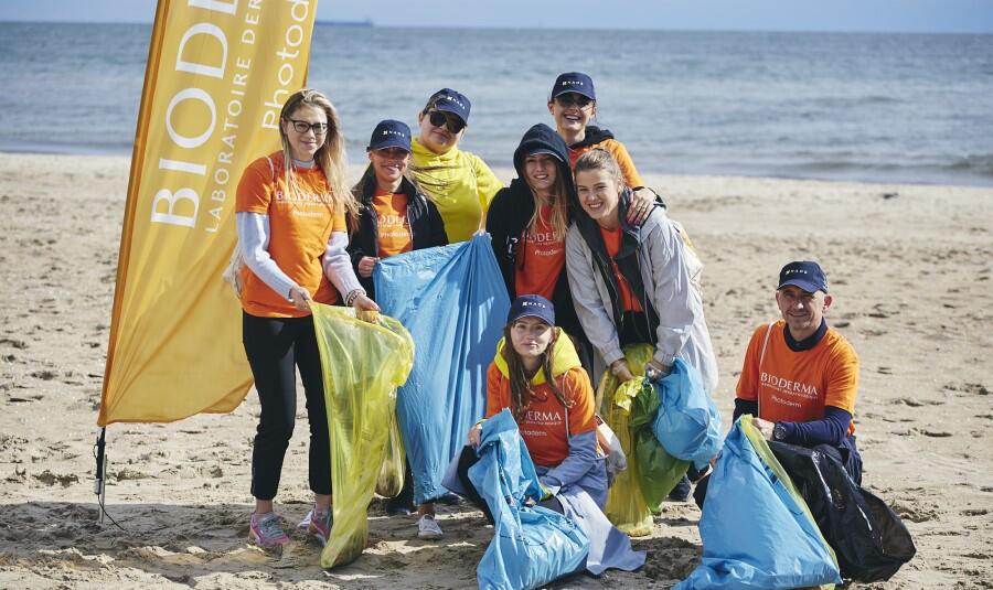 Uczestniczki i uczestnicy akcji podczas sprzątania plaży. Pozują z workami śmieci