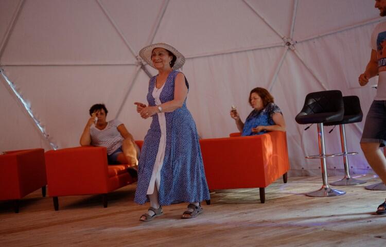 starsza kobieta w niebieskiej sukience i kapeluszu tańczy sama na parkiecie