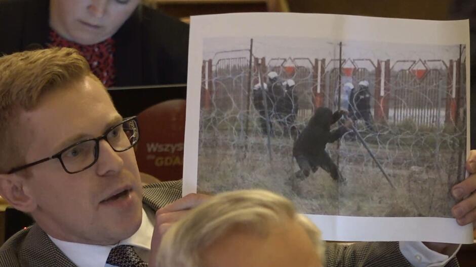 Radny PiS Andrzej Skiba wydrukował zdjęcia ze starcia imigrantów z polskimi służbami granicznymi, które prezentował podczas dyskusji. 