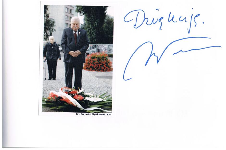 Karta albumu przedstawia zdjęcie, na którym Lechy Wałęsa składa kwiaty pod Pomnikiem Poległych Stoczniowców. Za Lechem Wałęsą stoi Pani Profesor. Na prawo od zdjęcia jest odręczny wpis: "Dziękuję" i autograf Lecha Wałęsy 