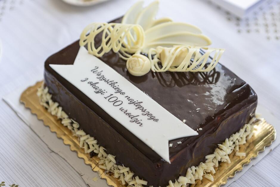 Prostokątny czekoladowy tort z napisem wszystkiego najlepszego z okazji 100 urodzin