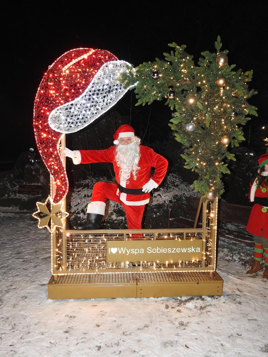 Mikołaj dumnie pozuje w świątecznym okienku - iluminacji, którą dostała Wyspa Sobieszewska za największą aktywność w głosowaniu na projekty Budżetu Obywatelskiego w 2022 r.