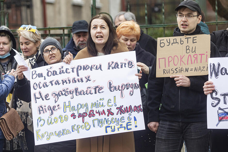 Kilkanaście osób z planszami z kartonu z napisami w języku rosyjskim i ukraińskim