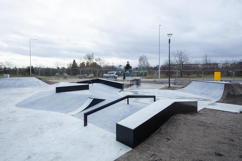 na zdjęciu nowy żelbetowy skatepark, widać różne podesty i barierki