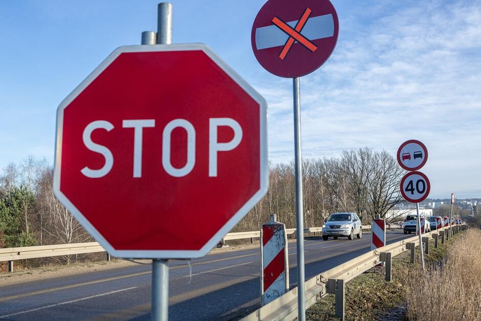 znaki ustawione przy drodze po której jadą samochody, na jednym napis stop 