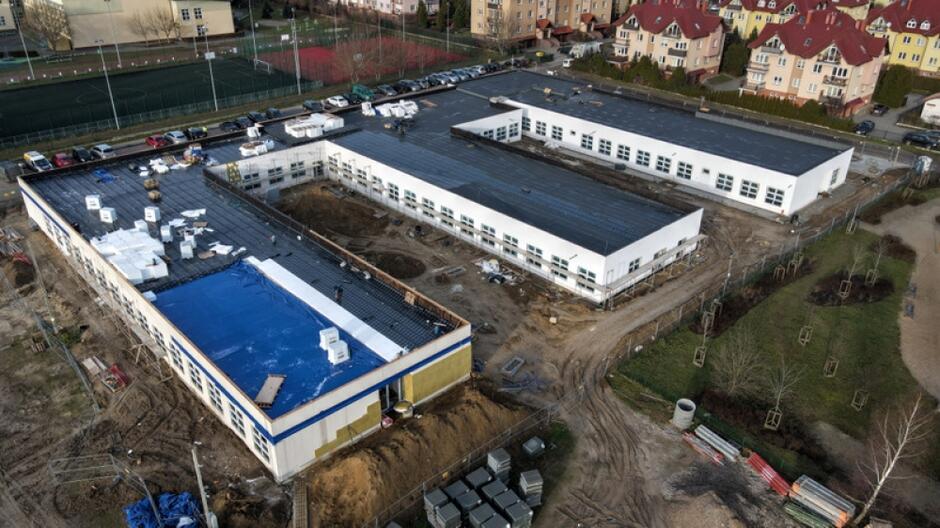zdjęcie z drona widać na nim nowy budynek szkolny zbudowany z trzech skrzydeł, budynek ma jeden poziom