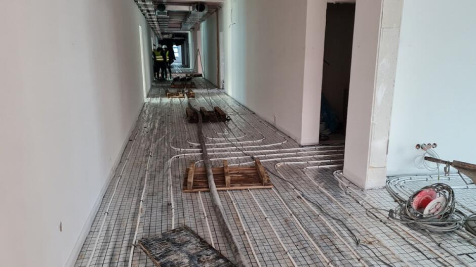 na zdjęciu korytarz w budowanej szkole, widać instalacje ułożone na podłodze i jasne ściany