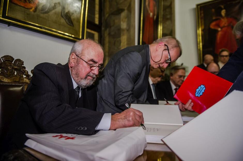 podpisywanie książki przez dwóch mężczyzn w garniturach