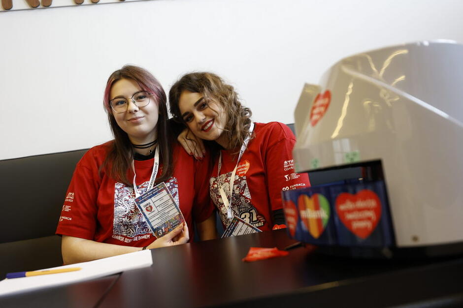 Dwie młode kobiety w czerwonych koszulkach siedzą przy stoliku