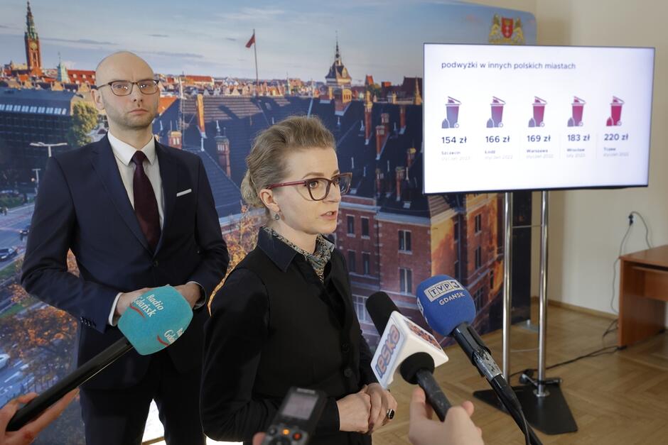 na zdjęciu olga goitowska mówi do mikrofonów dziennikarskich, za nią stoi wiceprezydent piotr kryszewski