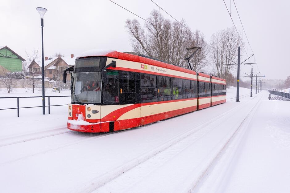 na zdjęciu biało-czerwony tramwaj, jedzie po torowisku, wokół mnóstwo śniegu