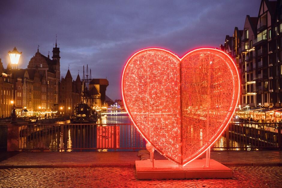 iluminacja świetlna w kształcie czerwonego serca na moście między kamienicami