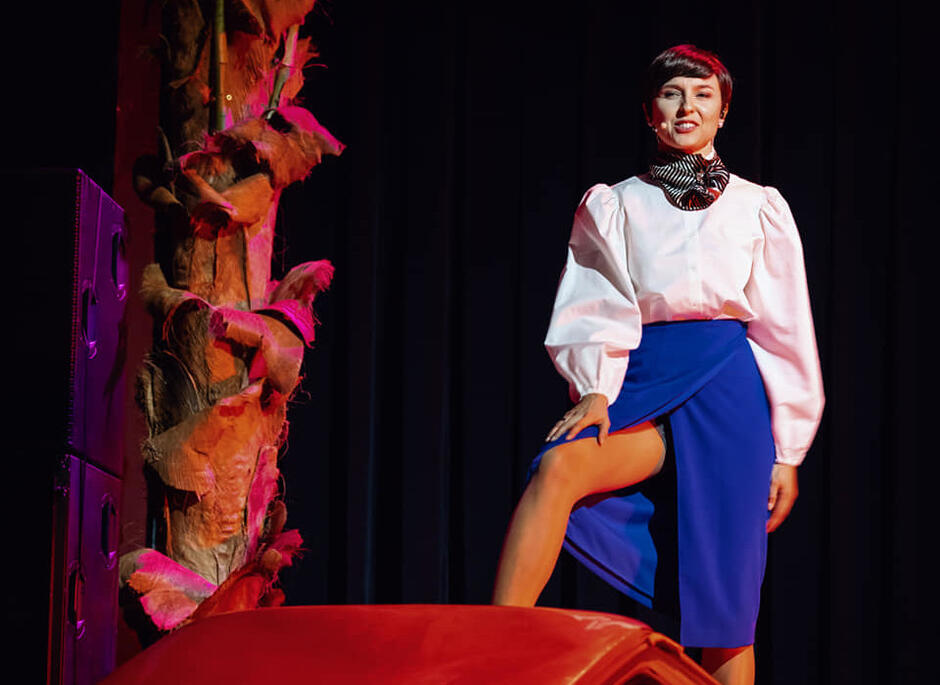 aktorka w dumnej postawie na przewróconym samochodzie - maluchu