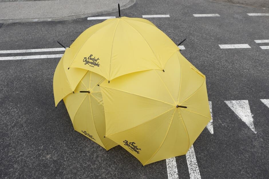 na zdjęciu kilka żółtych parasolek nałożone jedna na drugą, widać na nich czarny napis budżet obywatelski