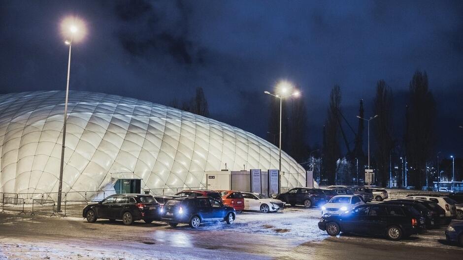 biała kopuła lodowiska, przed nią zaparkowane samochody 