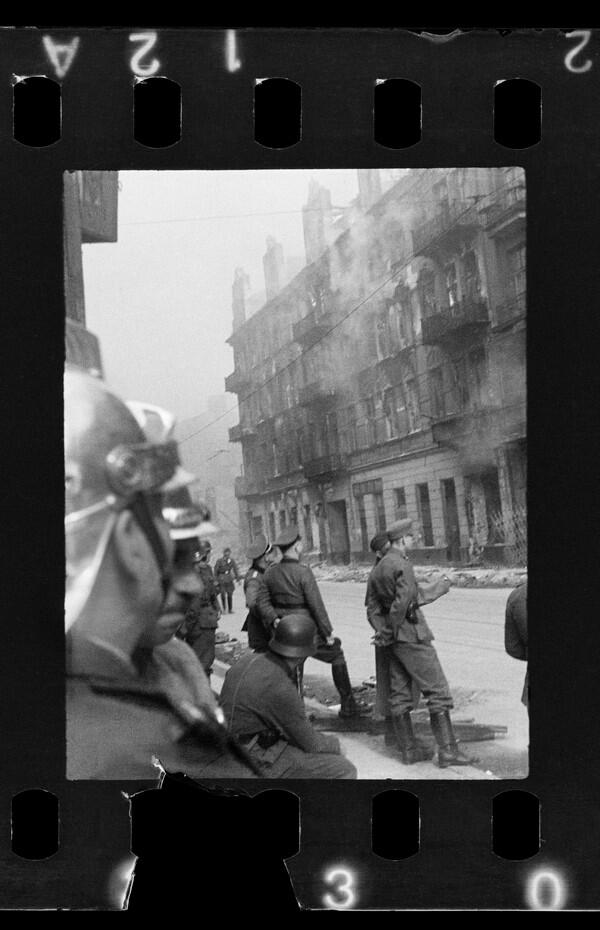 Czarno-białe zdjęcie: kilku żołnierzy niemieckich, w tym oficerów przed budynkiem piętrowym