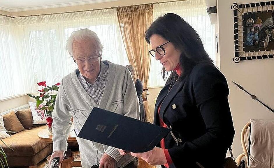 kobieta czyta tekst gratulacji starszemu mężczyźnie