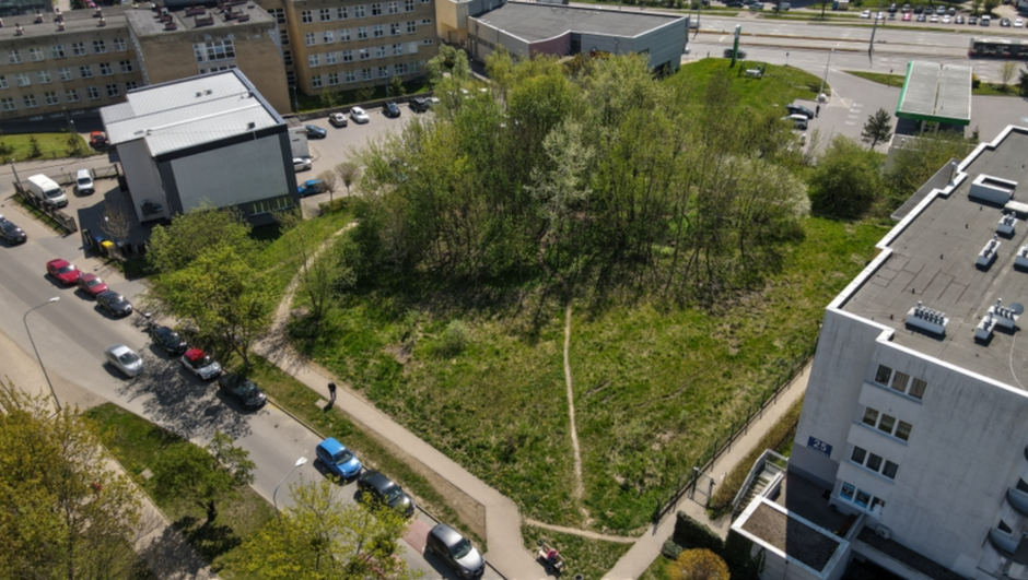 zdjęcie z drona, widać duży zielony teren z drzewami, po obu stronach otoczony kilkupiętrowymi budynkami