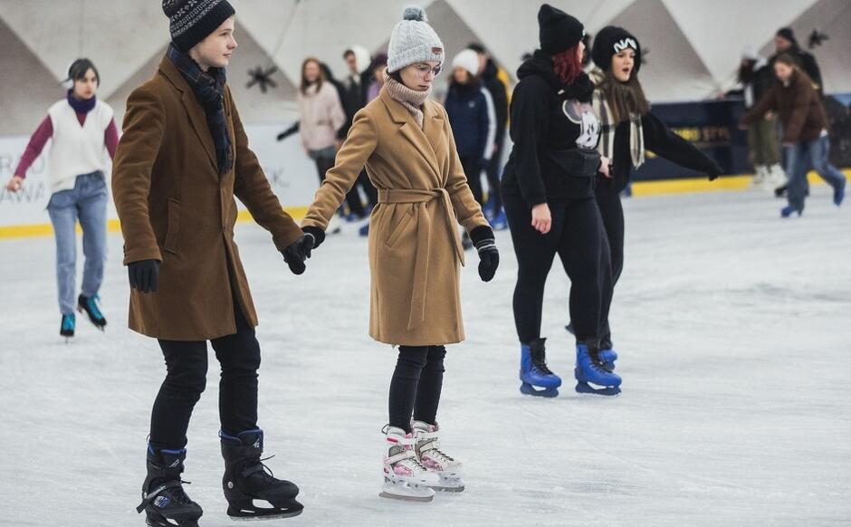 chłopak i dziewczyna trzymają się za ręce, nastolatki, ślizgają się na lodowisku