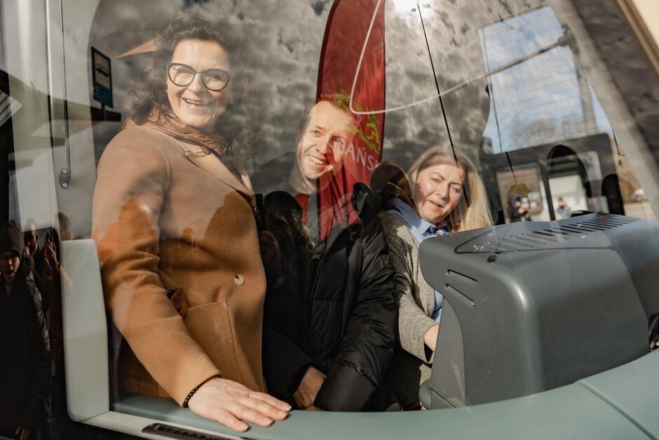 kokpit tramwaju od zewnątrz, pani motornicza, obok młody mężczyzna i kobieta wś średnim wieku