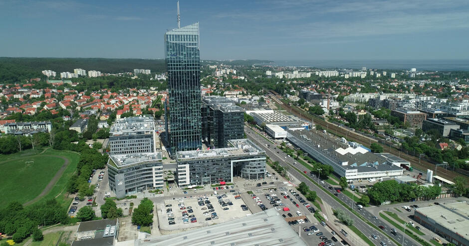 panorama miasta z wyróżniającym się wysokim na 34 piętra przeszklonym budynkiem, w tle zatoka