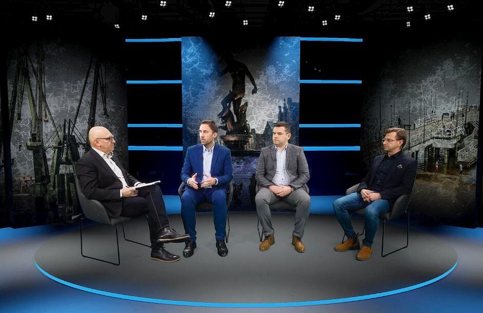 studio wirtualne, w którym siedzą na krzesłach czterej mężczyźni i rozmawiają