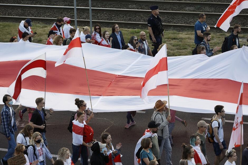 a group of demonstrators walked down the street and carried a large white-red-white flag